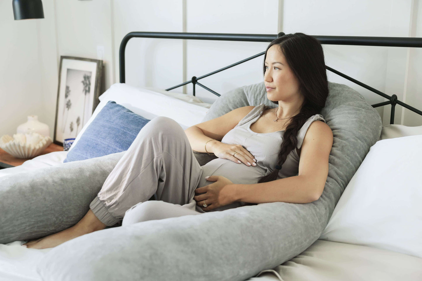 Woman lying on a Pregnancy Body Pillow in a bedroom setting