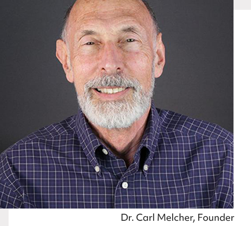 Doctor Carl Melcher. Smiling older man, white beard, wearing a checkered shirt, dark background.