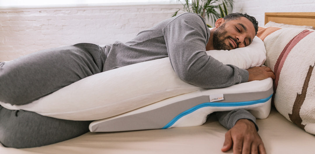 Man sleeping on his side using a therapeutic body pillow and wedge for shoulder support.