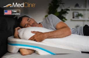 Man sleeping on MedCline shoulder relief system with inclined wedge and body pillow, TAA compliant