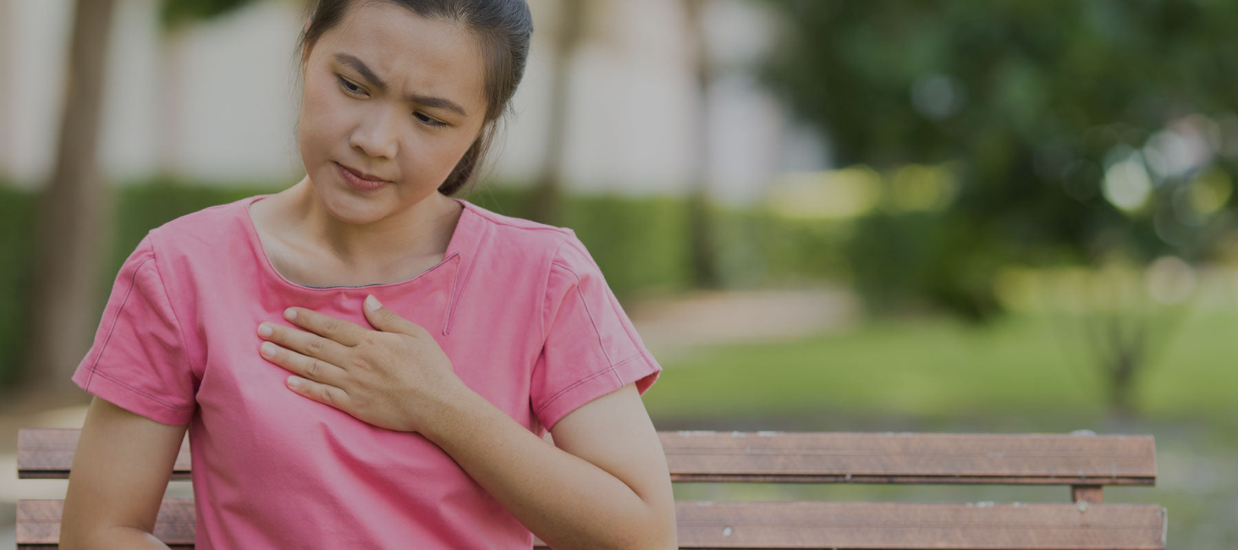 woman holding chest from heartburn