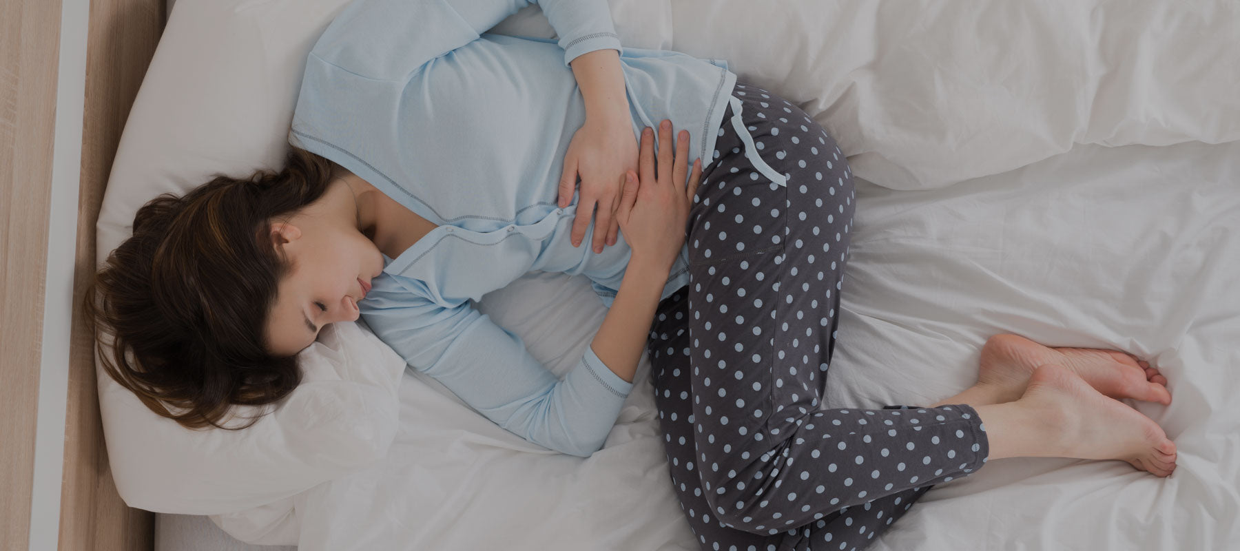 woman in bed holding her stomach with reflux pain