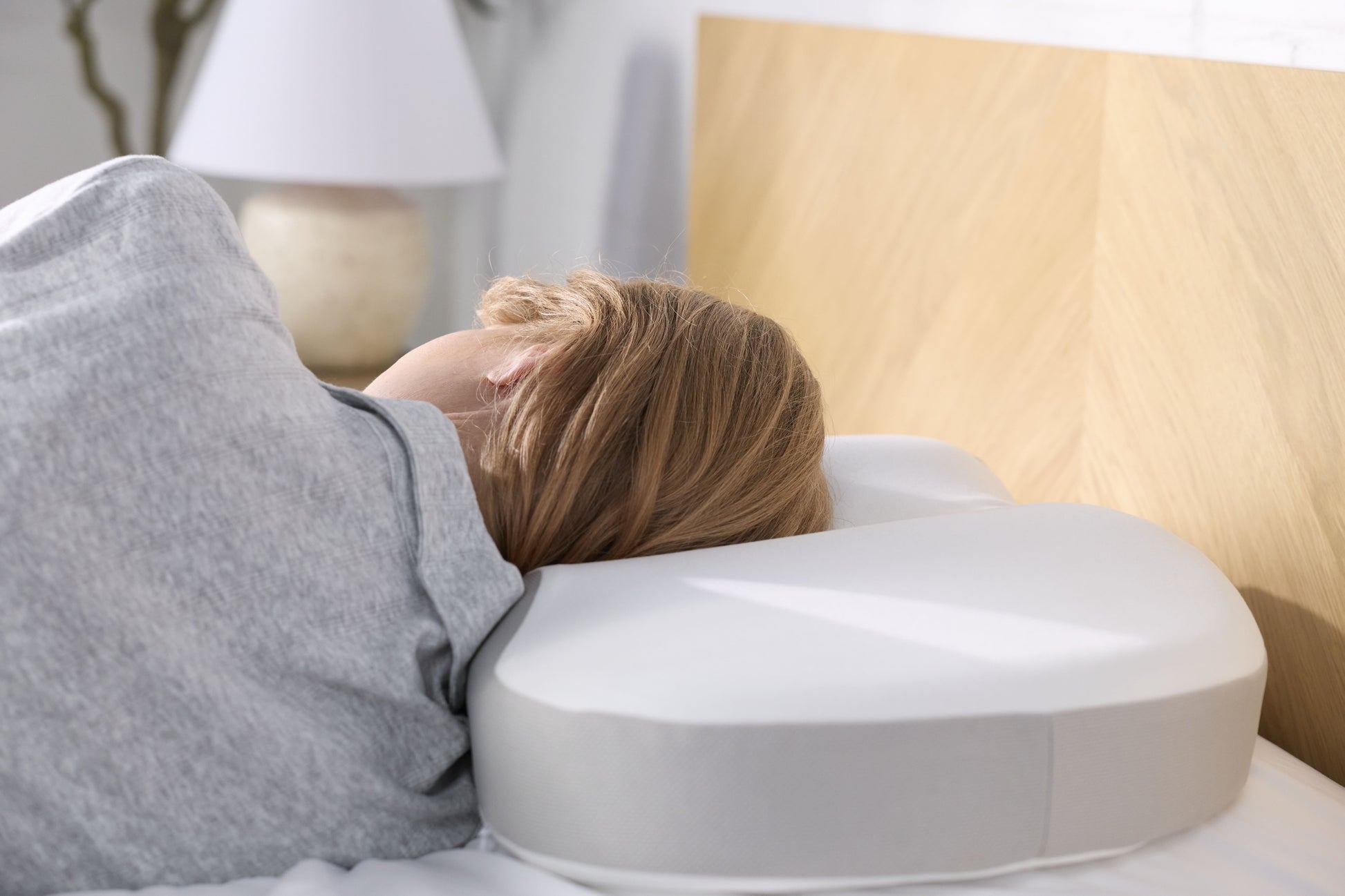 A woman lying on her side using the Multi-Position Neck Pillow