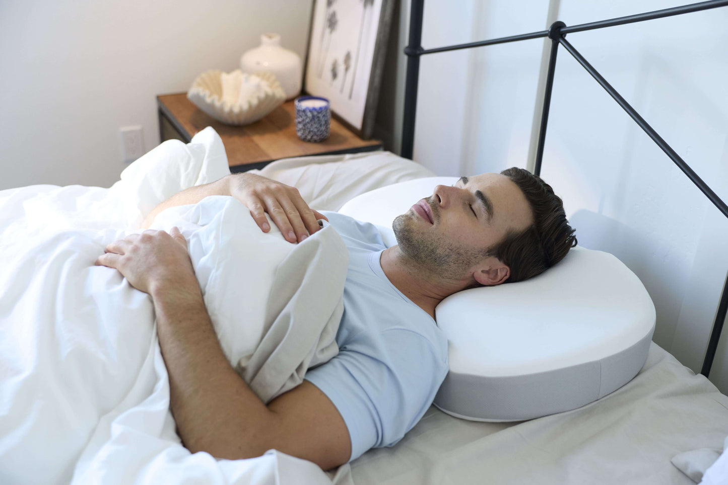 Man lying in bed using the Multi-Position Neck Pillow 