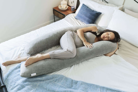 Woman lying on a bed with a Pregnancy Body Pillow