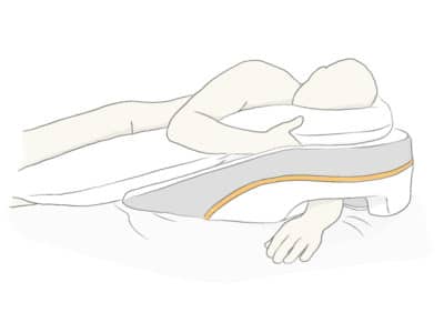 Illustration of a person lying on their side with one arm through the opening of the wedge pillow.