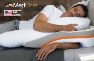 Man sleeping on MedCline reflux relief system with inclined wedge and body pillow, TAA compliant